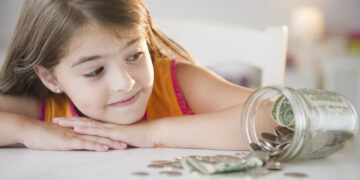 USA, New Jersey, Jersey City, Girl ( 6-7) looking at savings in jar